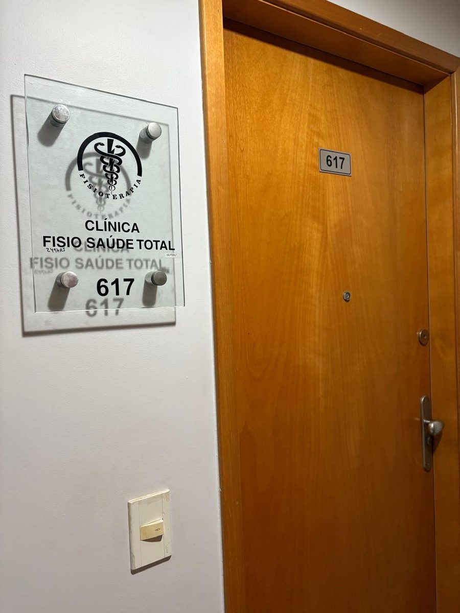 Porta da sala 617, com a placa de vidro da Clínica Fisio Saúde Total ao lado